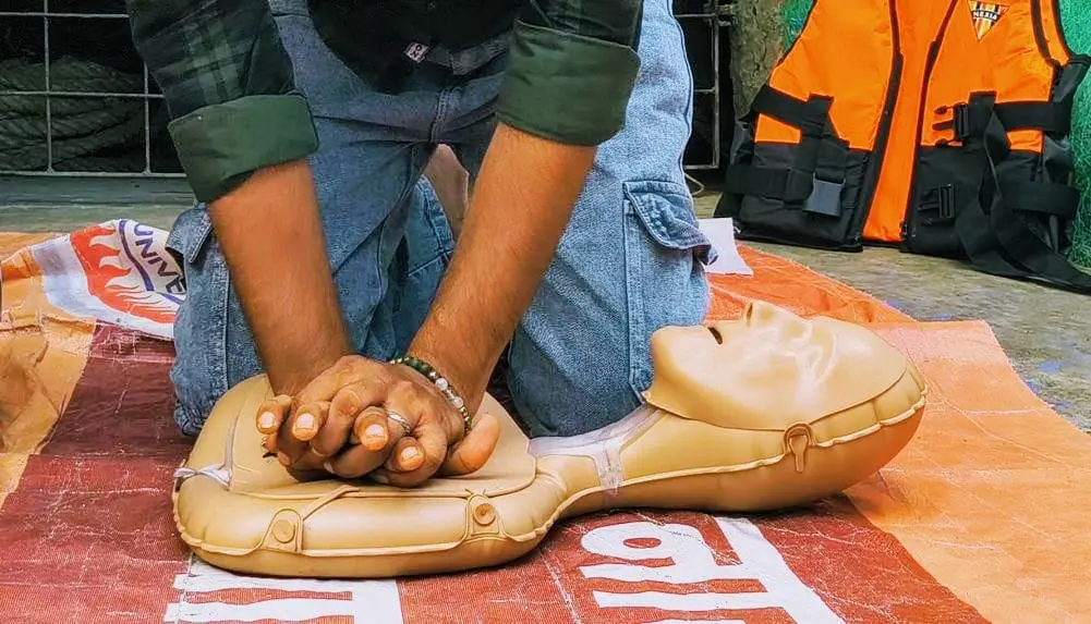 Close view of hands demonstrating CPR chest-compression technique on a manikin