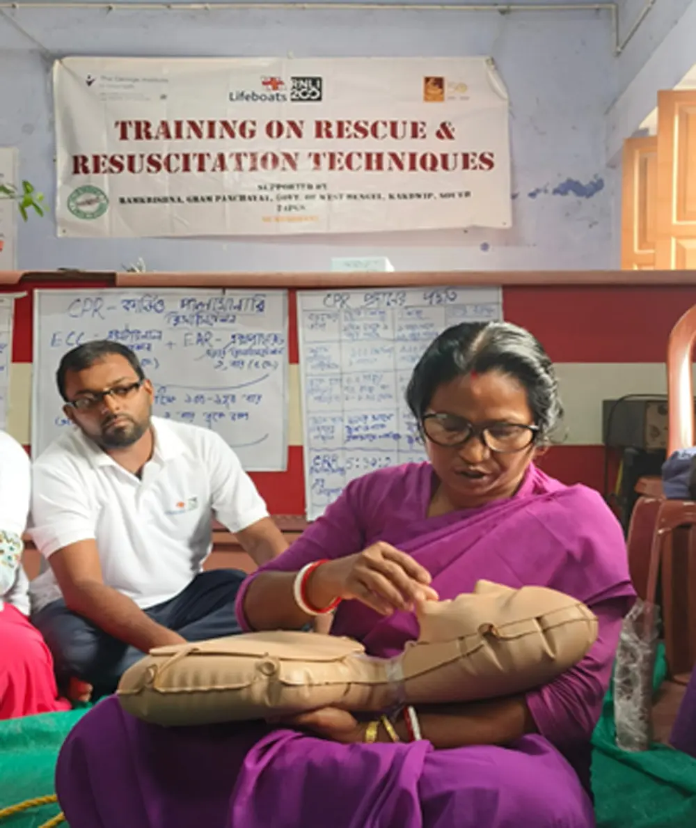 A woman practising infant resuscitation on a training manikin